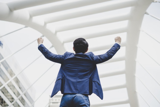 successfully-young-businessman-keeping-arms-raised-expressing-positivity-while-standing-outdoors_1150-3054